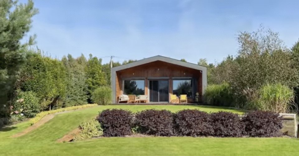 Nowoczesny dom nad jeziorem z drewnianą elewacją i dużymi przeszkleniami, zbudowany przez Simple House.